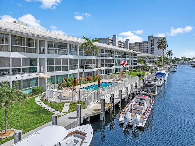 view of dock featuring a water view, a yard, a patio, and a fenced in pool