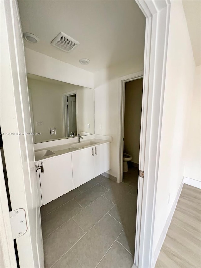 bathroom featuring hardwood / wood-style flooring, oversized vanity, and toilet