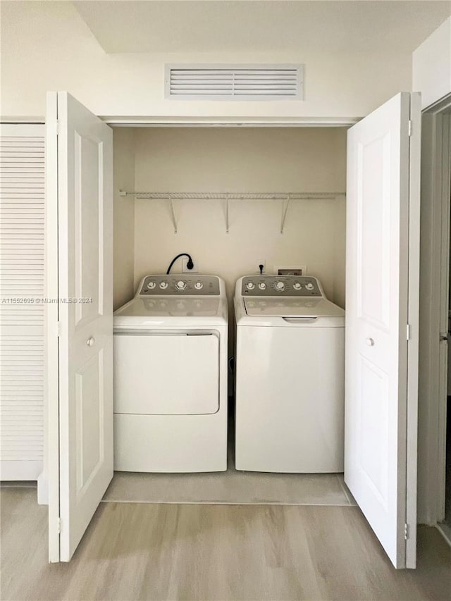 clothes washing area with washer and dryer, washer hookup, light hardwood / wood-style floors, and hookup for an electric dryer