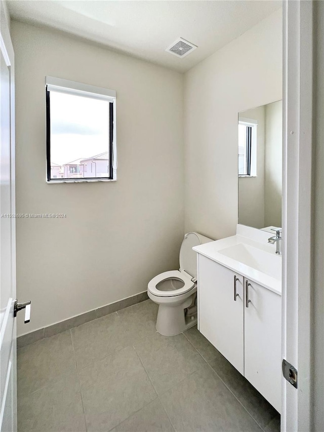 bathroom featuring toilet, tile flooring, and vanity