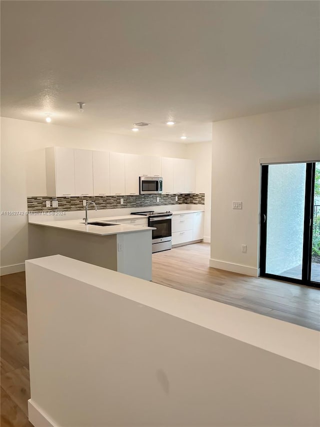 kitchen with white cabinetry, backsplash, sink, light wood-type flooring, and stainless steel appliances