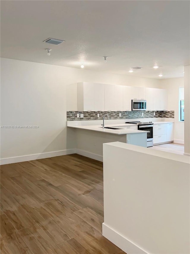 kitchen with light hardwood / wood-style floors, range with electric cooktop, tasteful backsplash, white cabinets, and sink