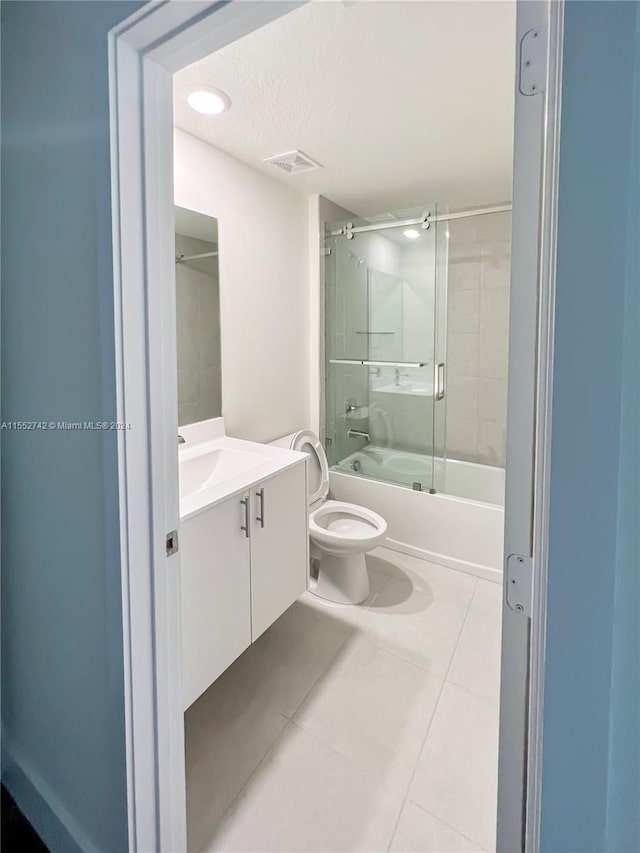 full bathroom with toilet, shower / bath combination with glass door, a textured ceiling, vanity, and tile floors