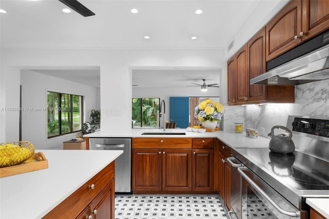 kitchen featuring kitchen peninsula, stainless steel appliances, sink, decorative backsplash, and ceiling fan