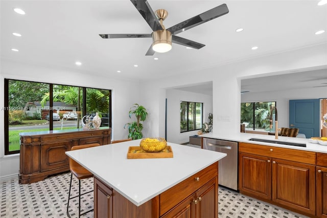 kitchen featuring dishwasher, a kitchen island, sink, ceiling fan, and a breakfast bar area