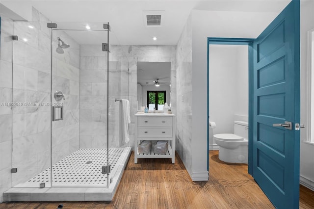 bathroom with a shower with door, toilet, wood-type flooring, ceiling fan, and vanity