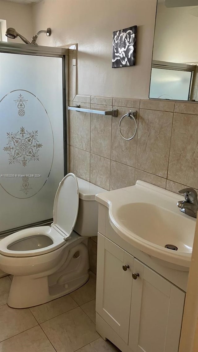 bathroom featuring toilet, vanity, tile patterned floors, and tile walls