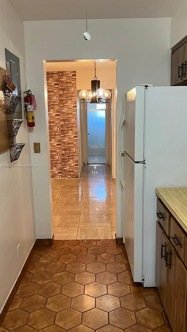 kitchen with light tile patterned flooring, hanging light fixtures, a notable chandelier, and white fridge