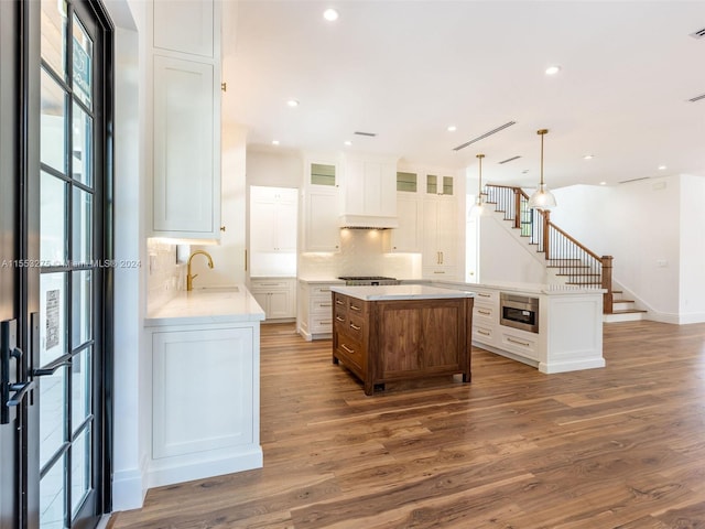 kitchen featuring white cabinets, a kitchen island, sink, and dark wood-type flooring