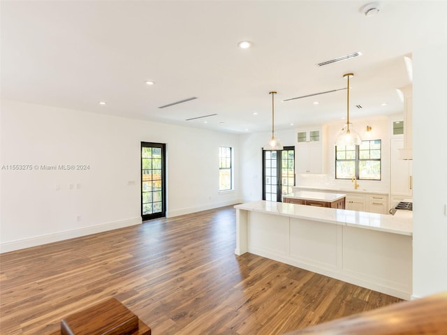 kitchen featuring white cabinetry, hardwood / wood-style floors, pendant lighting, decorative backsplash, and a breakfast bar