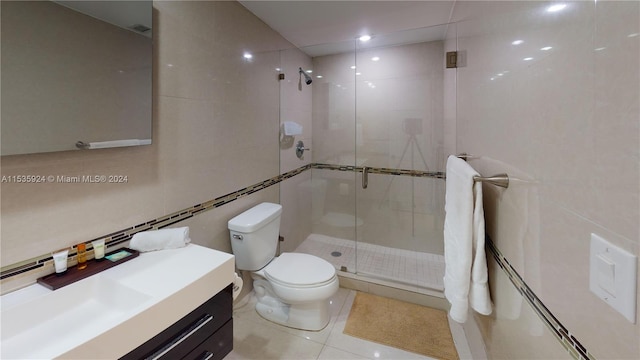 bathroom featuring toilet, vanity, walk in shower, tile walls, and tile flooring