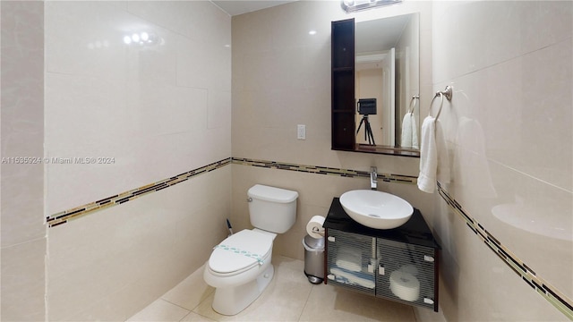 bathroom featuring tile walls, tile flooring, toilet, and vanity