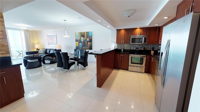 kitchen featuring decorative light fixtures, a tray ceiling, light tile flooring, appliances with stainless steel finishes, and tasteful backsplash