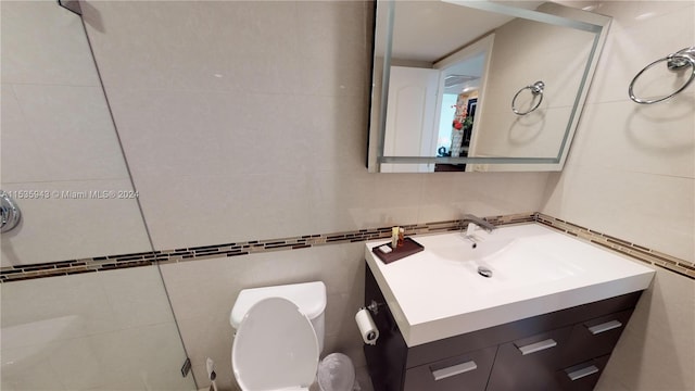 bathroom featuring tasteful backsplash, large vanity, toilet, and tile walls