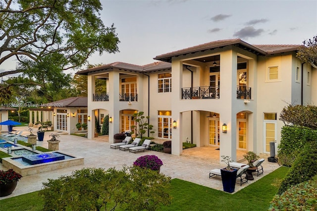 back of property with french doors, a patio, a balcony, and a hot tub