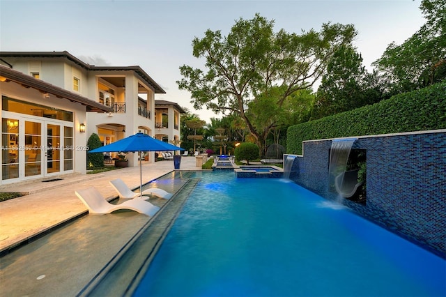 view of swimming pool featuring pool water feature, an in ground hot tub, a patio, and french doors