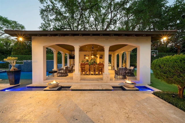 back house at dusk featuring a patio and a fire pit