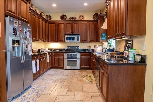 kitchen featuring stainless steel appliances, light tile floors, dark stone countertops, and sink