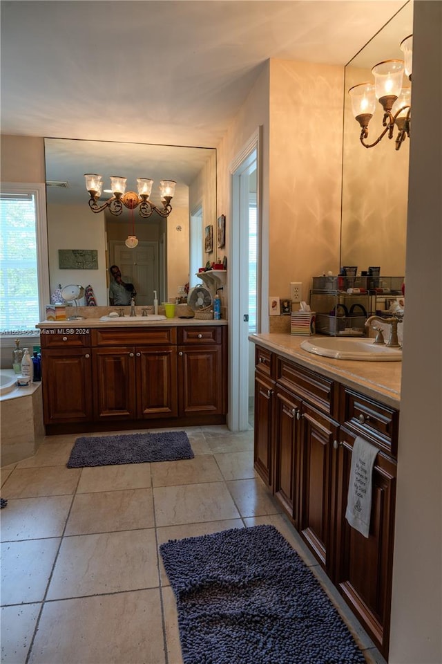 bathroom with an inviting chandelier, dual vanity, tile floors, and a bathing tub