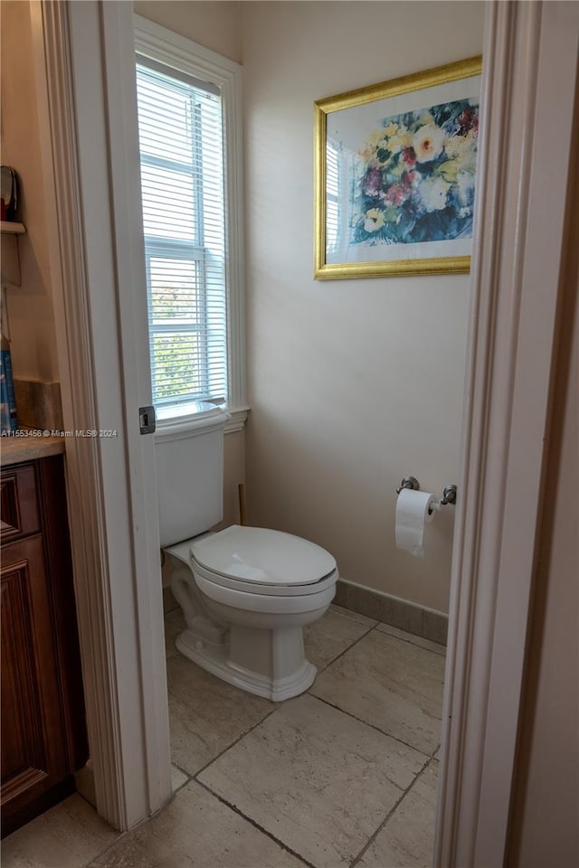 bathroom with toilet, vanity, a wealth of natural light, and tile flooring