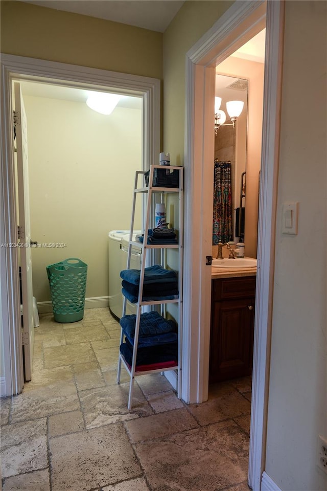 hall with a chandelier, light tile floors, sink, and washer / dryer