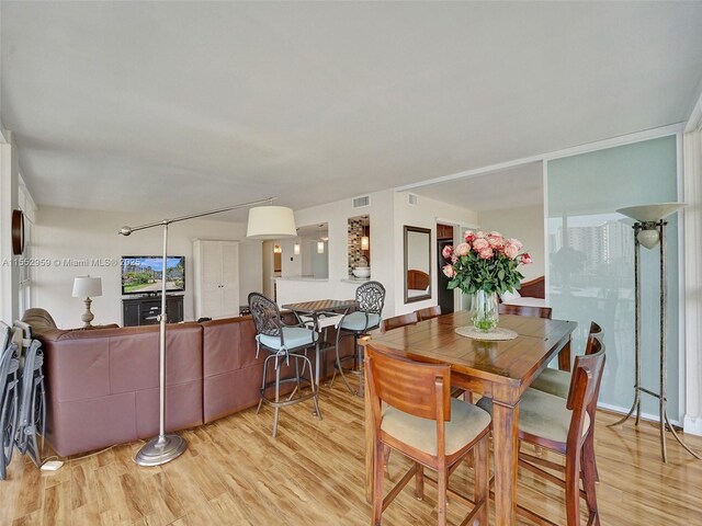 kitchen with kitchen peninsula, pendant lighting, sink, light hardwood / wood-style floors, and light stone countertops