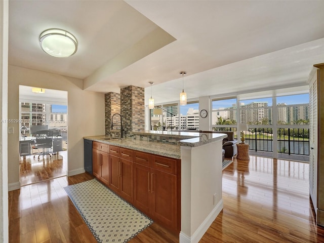 kitchen with sink, light stone counters, hanging light fixtures, plenty of natural light, and kitchen peninsula