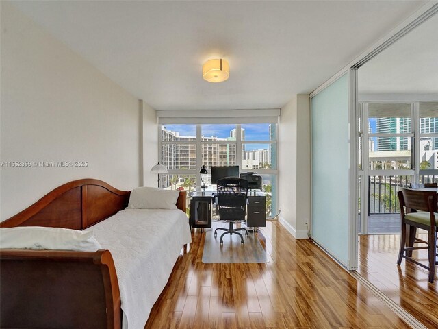 home office with light hardwood / wood-style floors and a wall of windows