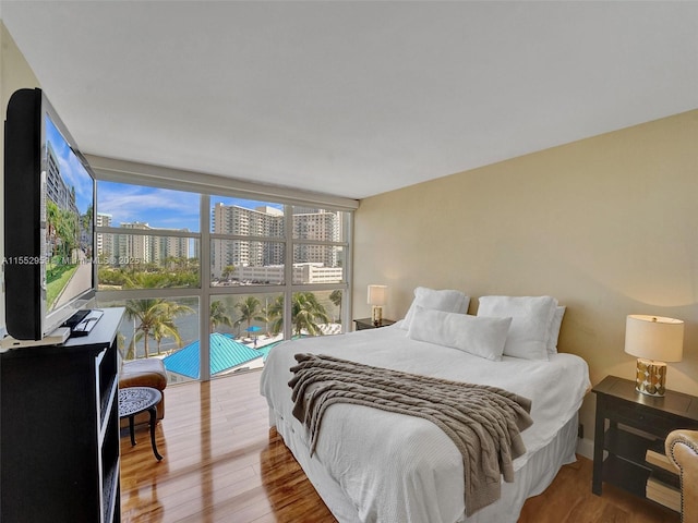 bedroom featuring expansive windows and hardwood / wood-style floors