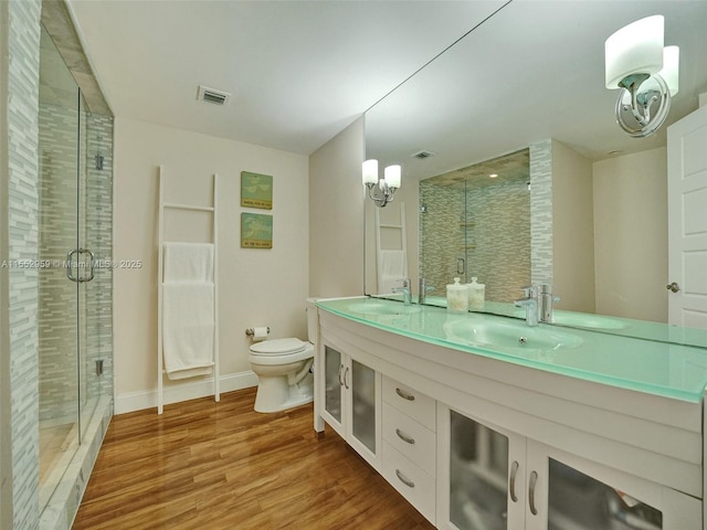 bathroom featuring a shower with door, vanity, hardwood / wood-style floors, and toilet