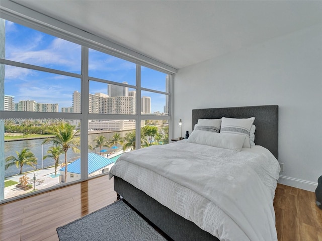 bedroom with a water view, wood-type flooring, and a wall of windows