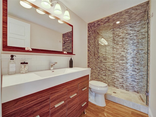 bathroom featuring toilet, a shower with door, vanity, wood-type flooring, and tile walls