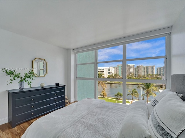 bedroom featuring wood-type flooring and a water view