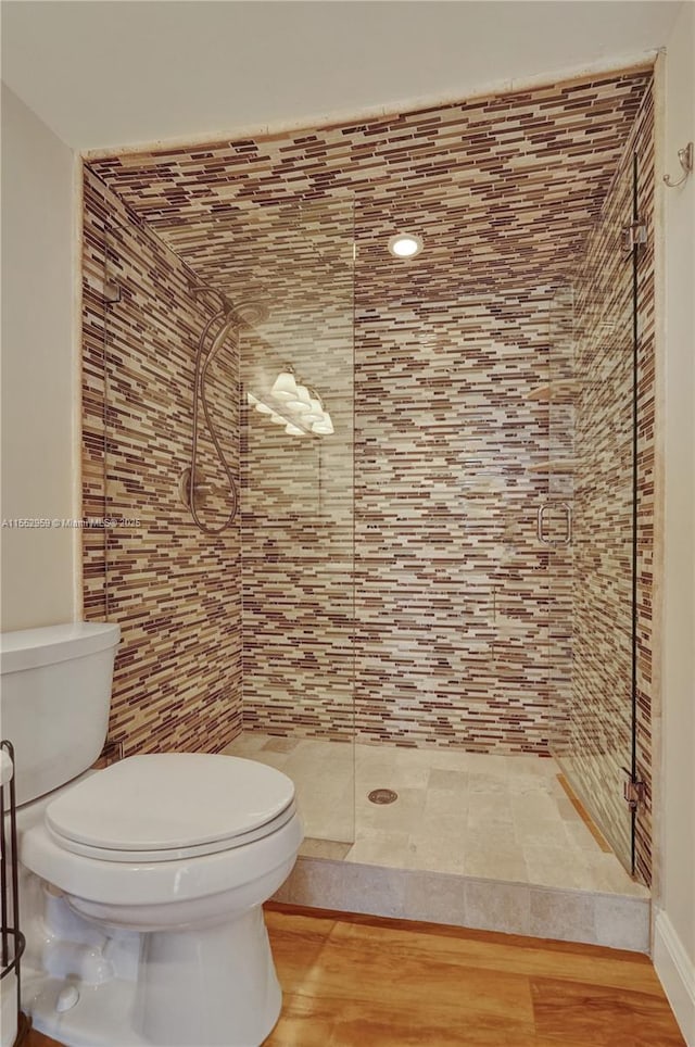 bathroom with hardwood / wood-style floors, toilet, and tiled shower