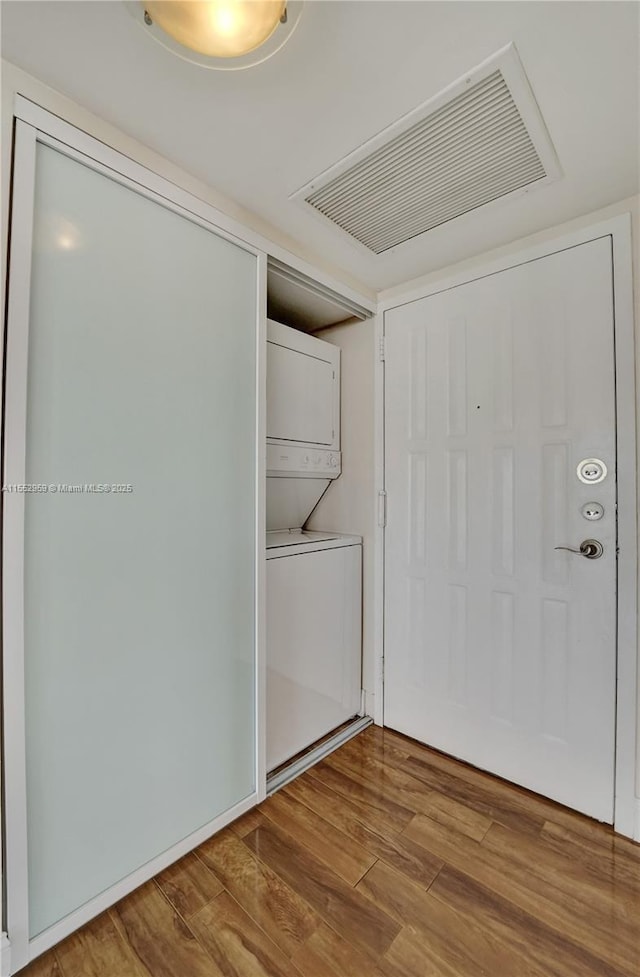 laundry area with stacked washer and dryer and hardwood / wood-style floors