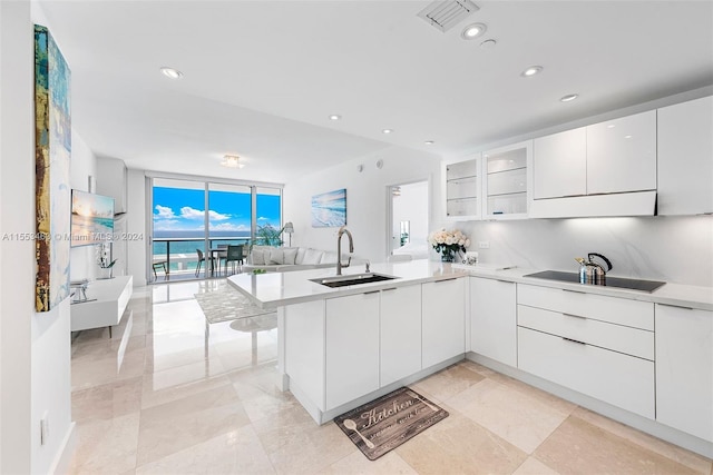 kitchen featuring expansive windows, white cabinetry, light tile flooring, sink, and black electric stovetop