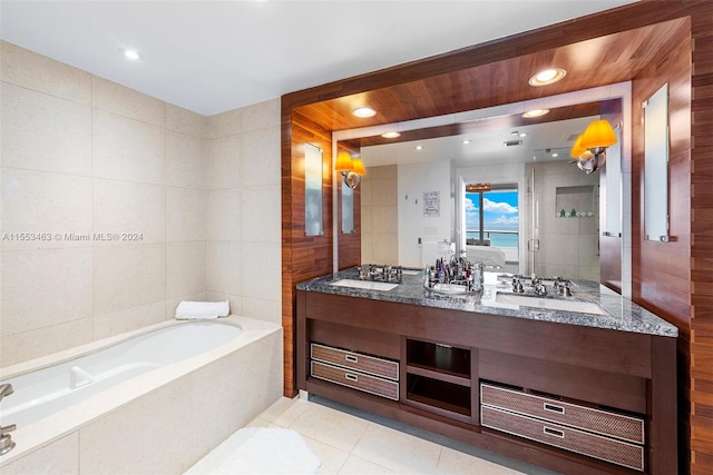 bathroom with tile flooring, double vanity, tile walls, and tiled bath