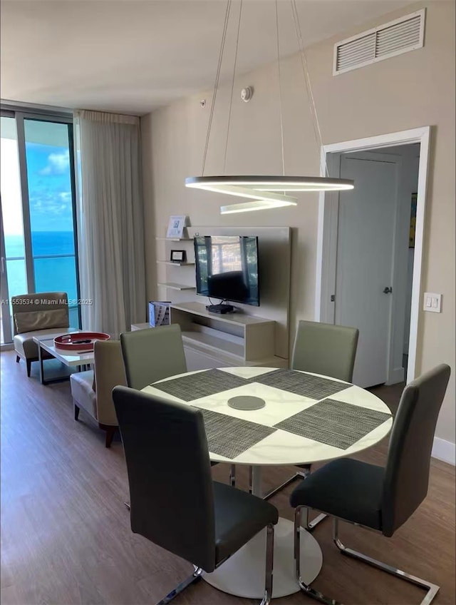 dining space with a wall of windows and hardwood / wood-style flooring