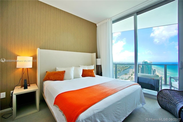 bedroom featuring a water view and floor to ceiling windows