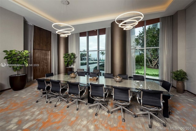 dining room with a wealth of natural light, a chandelier, a wall of windows, and a raised ceiling