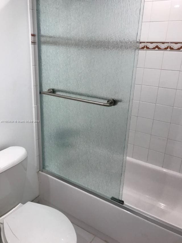 bathroom featuring shower / bath combination with glass door and toilet