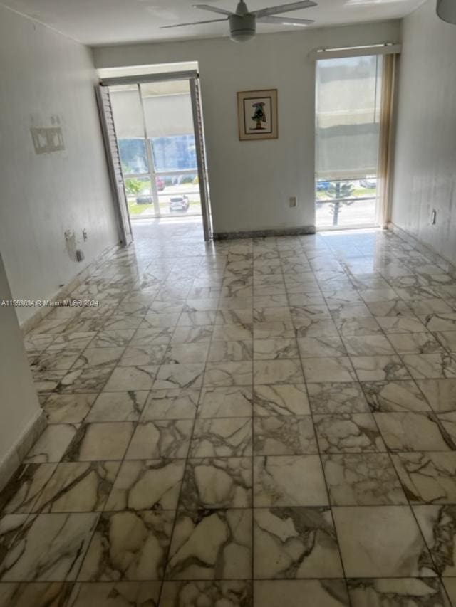 tiled spare room featuring ceiling fan