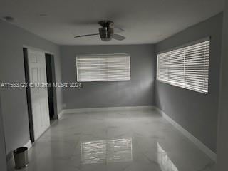 empty room featuring tile floors and ceiling fan