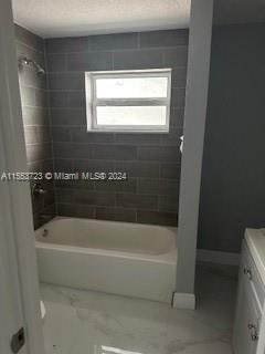 bathroom with tiled shower / bath, vanity, and tile floors