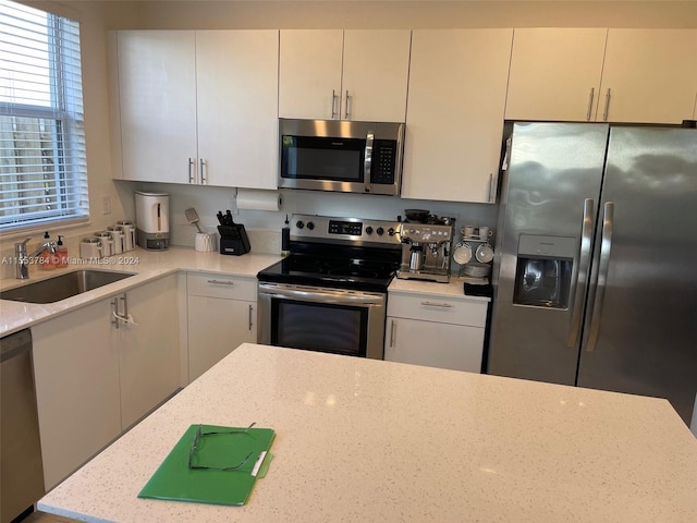 kitchen featuring white cabinetry, sink, light stone counters, and stainless steel appliances