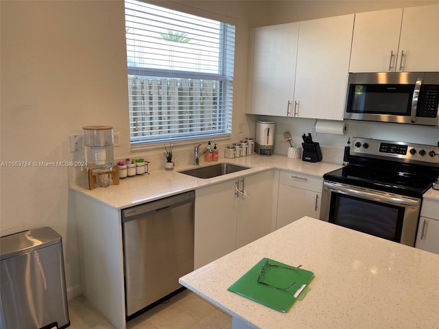 kitchen featuring appliances with stainless steel finishes, sink, white cabinets, and light stone counters