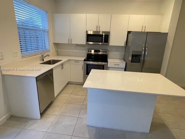 kitchen featuring a kitchen island, white cabinetry, appliances with stainless steel finishes, and sink