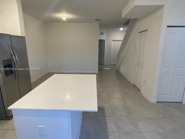 kitchen featuring a center island, stainless steel fridge with ice dispenser, and light tile patterned floors