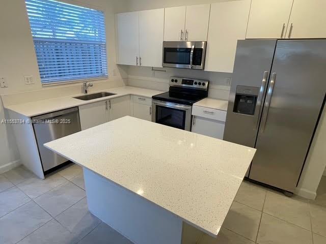 kitchen featuring stainless steel appliances, white cabinetry, sink, and light tile patterned floors