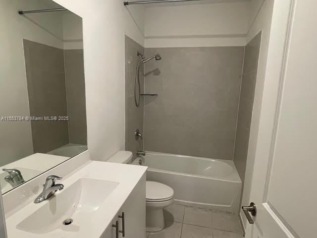 full bathroom featuring tile patterned flooring, vanity, tiled shower / bath combo, and toilet